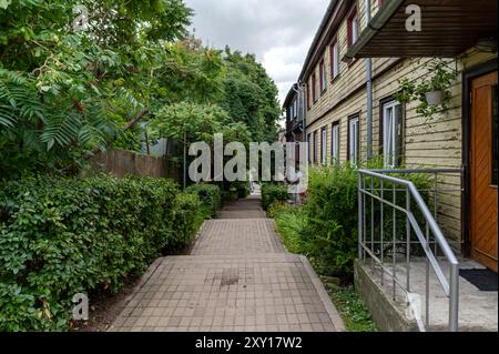 Tukums, Lettonie - 22 août 2024 : passerelle verte bordée d'arbres et de bâtiments par temps nuageux Banque D'Images