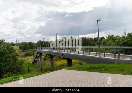 Tukums, Lettonie - 22 août 2024 : un pont piétonnier relie des zones de verdure par temps couvert. Banque D'Images