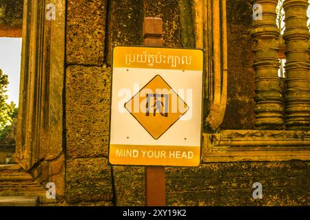 Affiche bilingue « Mind Your Head ». Temple Banteay Srei, parc archéologique d'Angkor, province de Siem Reap, Cambodge. © Brooks Lieb Banque D'Images