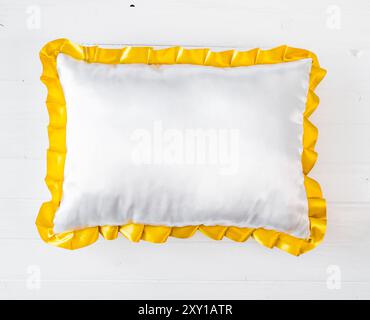 Oreiller blanc avec volants dorés sur une table blanche Banque D'Images