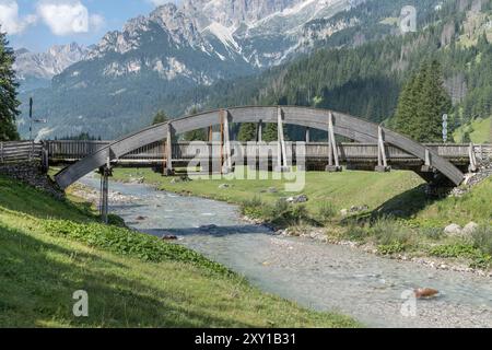 Paysage avec pont en bois sur la rivière Avisio et la chaîne de montagnes Catinaccio en arrière-plan, tourné de l'est dans la lumière d'été à Fontanazzo di Fassa Banque D'Images