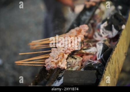 Satay kambing ou satay chèvre, agneau, agneau ou viande de chèvre satay avec des ingrédients de charbon de bois sur le feu rouge grill par les gens. Satay traditionnel de yogyakarta, Banque D'Images