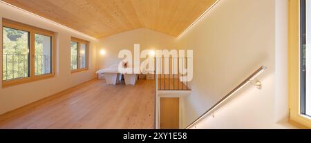 Vue panoramique de face d'une chambre meublée avec des meubles en carton, avec un lit et des chaises confortables. Sur la droite se trouve l'escalier qui descend au L. Banque D'Images