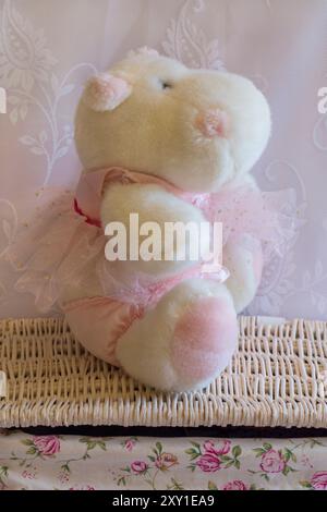 jouet hippopotame doux en peluche portant une robe rose et un pantalon par d s nicholas ltd assis sur un panier en osier Banque D'Images