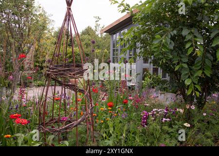 Un support de plante wiilow wigwam dans une bordure d'été colorée de Zinnia elegans 'Giant Dahlia Mix', Digitalis 'Ruby Glow', Allium 'Summer Drummer' et Pen Banque D'Images