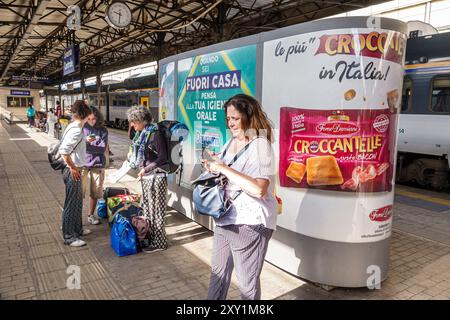 Livourne Italie, Piazza Dante, gare centrale de train Livourne, passagers de plate-forme femmes en attente, kiosque de panneaux publicitaires, Forno Damiani Banque D'Images