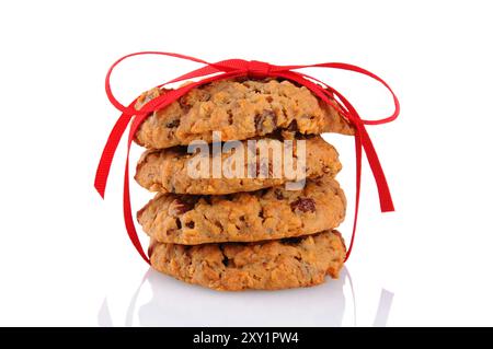 Gros plan d'une pile de biscuits à la farine d'avoine raisin attachés avec un ruban rouge, isolé sur blanc. Banque D'Images