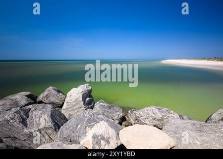 « Mexico Beach, Floride, États-Unis, possède des jetées rocheuses encadrant des eaux bleu émeraude, se mélangeant parfaitement avec des plages de sable blanc sous un ciel bleu serein, de Banque D'Images