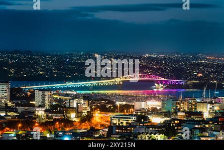 Pont illuminé couleur arc-en-ciel traversant la mer par le port d'Auckland en Nouvelle-Zélande Banque D'Images