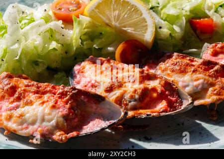 moules cuites au four avec du caviar masago et du fromage sur une assiette blanche avec du citron Banque D'Images