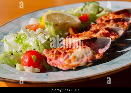 moules cuites au four avec du caviar masago et du fromage sur une assiette blanche avec du citron Banque D'Images