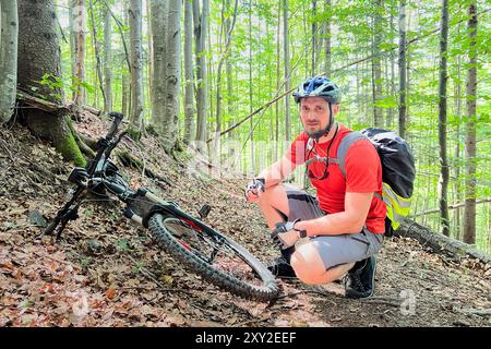 Portrait de l'homme pompant roue de vélo. Cycliste gonfle la roue de bicyclette à l'aide d'une pompe. Pompage de l'air dans une roue vide de vélo. Banque D'Images