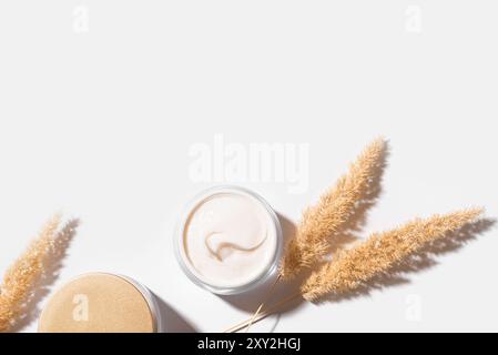 Crème de beauté cosmétique avec de l'herbe sèche naturelle isolé sur fond blanc, vue de dessus, espace de copie. Crème anti rides nourrissante, éco SK naturelle Banque D'Images