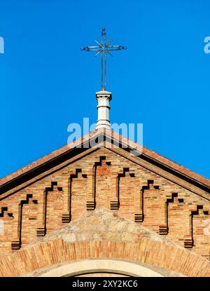 Pignon d'une ancienne chapelle avec une croix sur le dessus du toit au-dessus d'un ciel bleu clair Banque D'Images