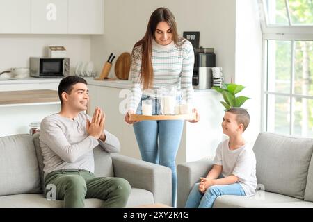 Jeune femme apportant un plateau avec du lait et des biscuits à sa famille à la maison Banque D'Images