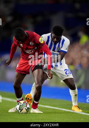 Ade Adeyemo de Crawley Town (à gauche) et Carlos Baleba de Brighton & Hove Albion se battent pour le ballon lors du match de deuxième tour de la Carabao Cup à l'American Express Stadium de Brighton. Date de la photo : mardi 27 août 2024. Banque D'Images