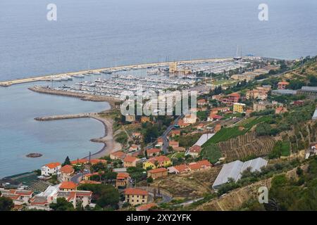 Une ville italienne pittoresque nichée le long d'une côte rocheuse, présentant un port rempli de bateaux, une route sinueuse et des vignobles verdoyants qui s'étendent vers le haut Banque D'Images