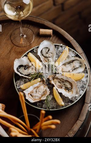 Huîtres élégantes sur glace avec citron et vin blanc, parfaites pour les repas gastronomiques et les occasions spéciales Banque D'Images