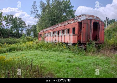 Une voiture de train de voyageurs d'époque est désaffectée à Cooperstown Junction, New York, reposant dans un champ, montrant son charme rustique. Banque D'Images