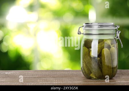 Pot avec des concombres marinés sur une table en bois à l'intérieur, espace pour le texte Banque D'Images