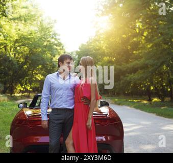 Couple heureux près de la red cabriolet dans une journée ensoleillée Banque D'Images