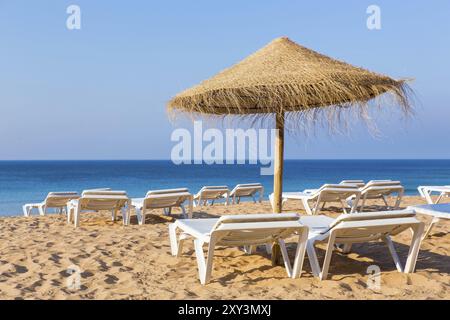 Wicker beach parasol with beach beds at blue sea Stock Photo