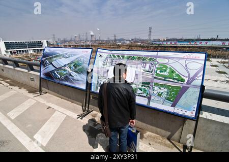 Un homme lisant les informations sur la nouvelle gare de Wuhan. Les trains à grande vitesse pour Guangzhou et Pékin partent de cette station. Banque D'Images