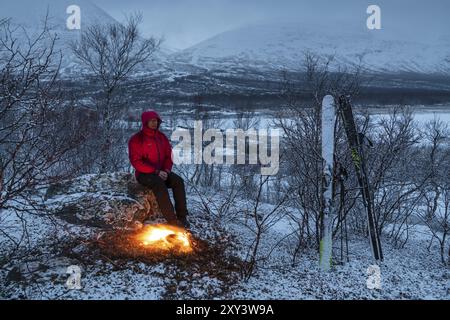 Homme sur un feu de camp, Stora Sjoefallet National Park, Laponie World Heritage site, Norrbotten, Laponie, Suède, avril 2018, Europe Banque D'Images