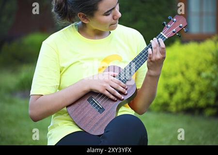 Cute girl jouant son ukulele en plein air dans la soirée Banque D'Images