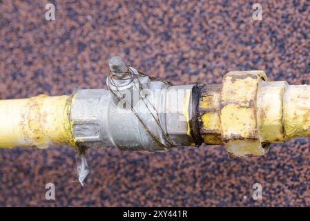 Un tube à gaz jaune, avec robinet, à l'extérieur d'une maison pour canaliser l'énergie douce à la maison Banque D'Images