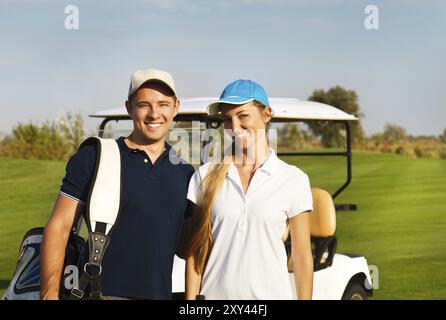 Jeune couple sportif jouer au golf sur un parcours de golf. Debout près de l'golfcar Banque D'Images