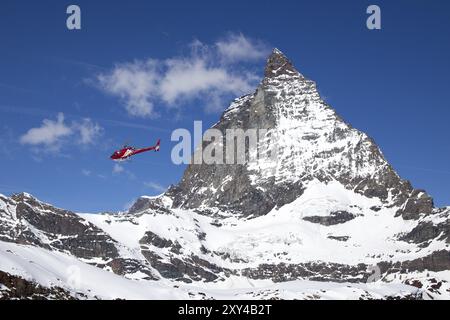 Zermatt, Suisse, 13 avril 2017 : un hélicoptère de sauvetage rouge volant à côté du célèbre Cervin, en Europe Banque D'Images