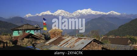 Vue d'un village près de Ghale Gaun, zone de conservation de l'Annapurna, Népal. Chaîne Manaslu enneigée. Maïs sur l'épi stocké à côté d'une ferme Banque D'Images