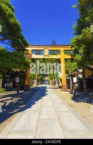 Entrée de la porte torii en bois au sanctuaire Shinto Sakurayama Hachiman-gu lors d'une journée de ciel bleu clair à Takayama, préfecture de Hida, Japon. Vertical Banque D'Images