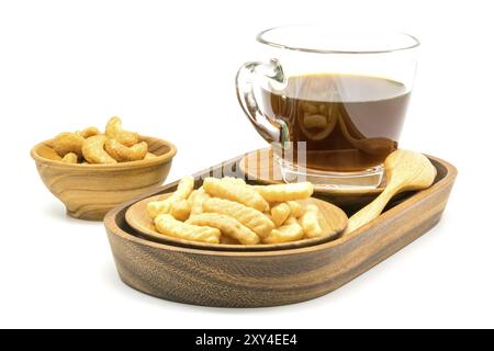 Craquelin aux crevettes et une tasse de café noir dans un plateau en bois avec des noix de cajou salées dans un bol en bois sur fond blanc Banque D'Images