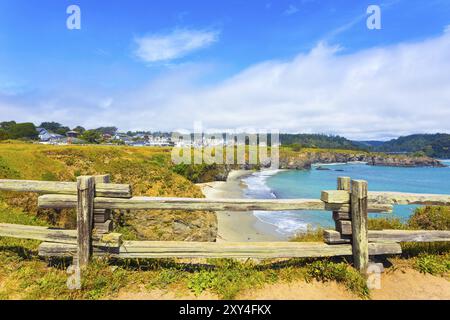 Vue à travers la clôture en bois rustique de la plage de sable en dessous de main Street et les maisons de la communauté de la ville de Mendocino sur une journée d'été ensoleillée en Californie. Horizont Banque D'Images