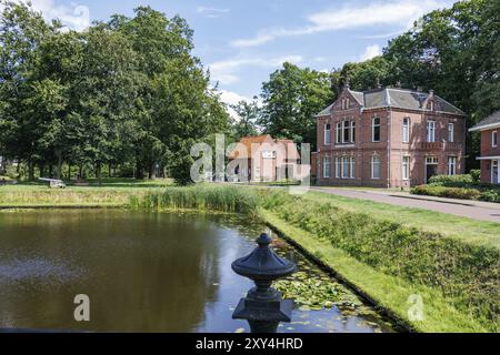 Deux bâtiments en briques sur la rive dans un paysage de parc verdoyant avec des arbres et des lanternes en été, aalten 2 Banque D'Images