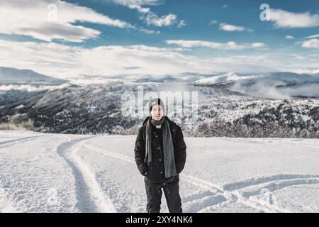 Jeune homme adulte debout, regardant la caméra souriante, à la station de ski de stryn, norvège en hiver avec beaucoup de neige, paysage de montagne avec des forts dedans Banque D'Images