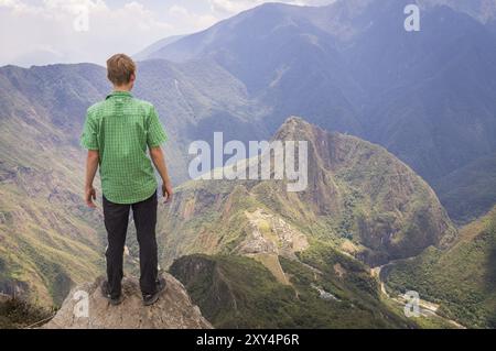 Un touriste sur la montagne Machu Picchu regarde vers le bas la mystérieuse ville Inca 600m plus bas, Machu Picchu, PÉROU en octobre 2015 Banque D'Images