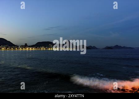 La plage de Copacabana et le Pain de Sucre vu la nuit avec ses bâtiments, l'éclairage, la mer, les collines et les contours Banque D'Images