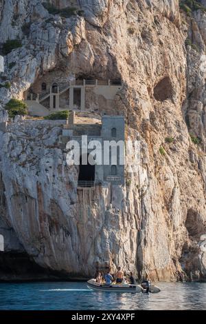 Masua, Italie - 23 août 2023 : falaise au-dessus de la mer à Masua, sur l'île de Sardaigne avec la mine abandonnée Porto Flavia au milieu du mur. Un vieux et Banque D'Images