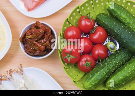 Nature morte de la nourriture crue dans des assiettes blanches sur une table en bois. Saumon congelé sur une assiette à côté de concombres et tomates fromage râpé et crevettes crues en bre Banque D'Images