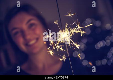 Smiling girl holding est un cierge magique dans sa main, la piscine, les lumières en arrière-plan Banque D'Images