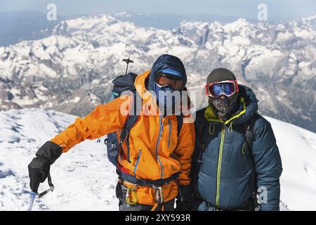 Portrait Un grimpeur d'âge moyen dans une veste en duvet il se tient debout à côté de son ami sur le chemin du sommet d'une montagne enneigée. Le concept de repos Banque D'Images