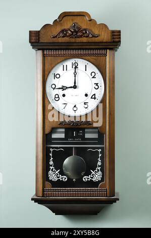 Photo stock d'une vieille horloge avec un pendule sur un mur montrant neuf Banque D'Images