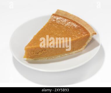 Un morceau de tarte à la citrouille sur une soucoupe isolé sur fond blanc Banque D'Images