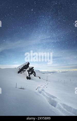 Un beau paysage nocturne. Un sentier sinueux dans les déneiges à côté de la roche pointue et de la crête du Caucase avec une montagne elbrus en arrière-plan Banque D'Images