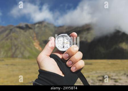 Prise de vue ViewPoint. Une vue à la première personne de la main d'un homme tient une boussole sur le fond d'un paysage épique avec des falaises collines et un ciel bleu avec Banque D'Images