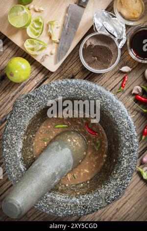 Pâte de crevettes sauce piment dans une pierre de mortier avec des ingrédients à cuire Banque D'Images