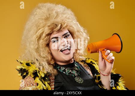 Une drag queen avec une grande perruque blonde sourit tout en tenant un mégaphone. Banque D'Images